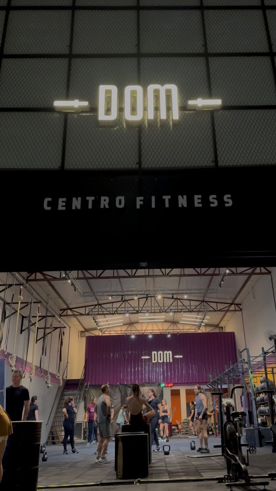 Letreiro DOM na fachada e turma treinando ao fundo