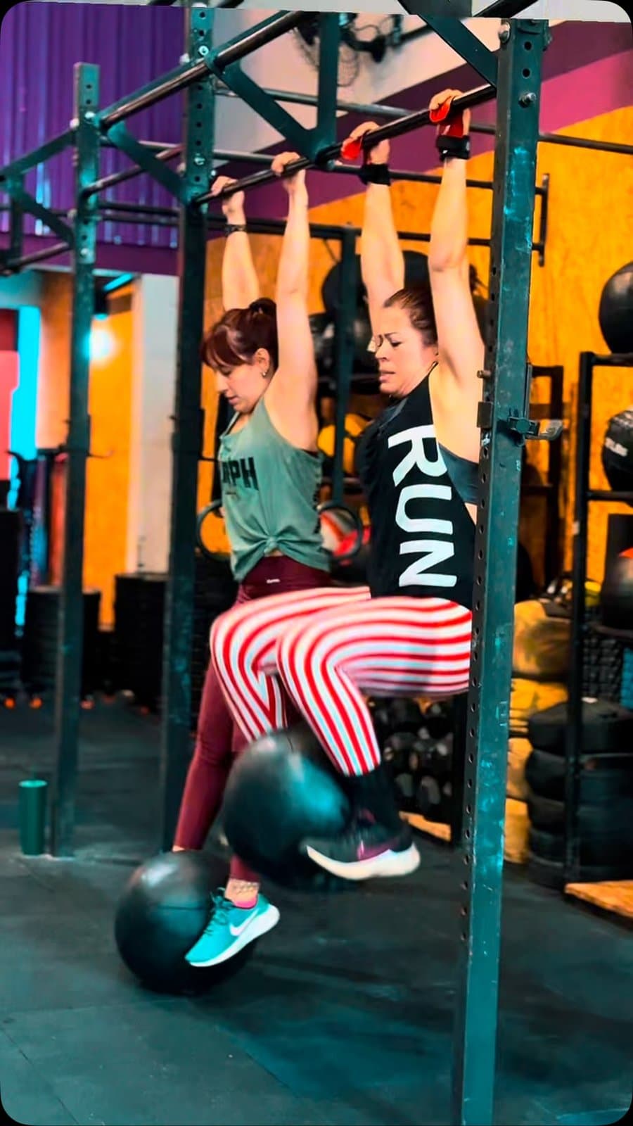 Duas alunas na barra fixa durante o WOD
